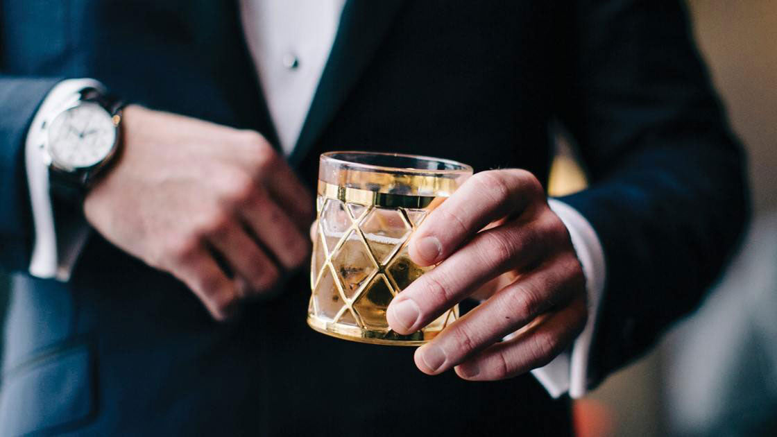 Corporate professional holding a glass of scotch he received as a gift.